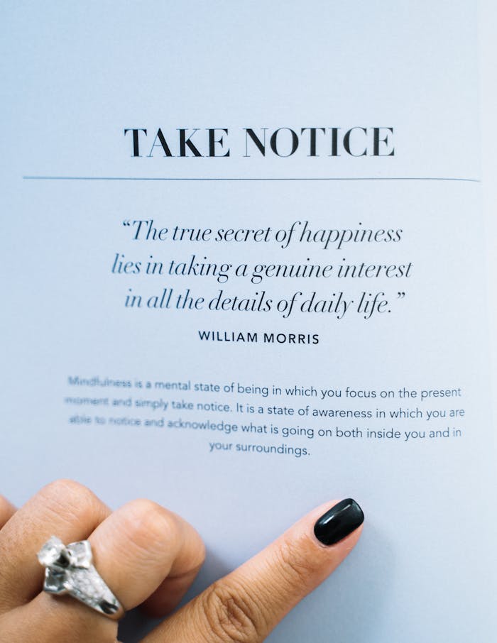 A woman's hand with a ring points to a mindfulness quote in a book.