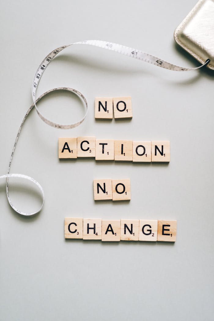 creative Scrabble tiles form motivational message ‘No Action No Change’ with a measuring tape.